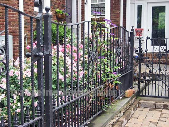 custom iron fencing installed near flowers at the gate